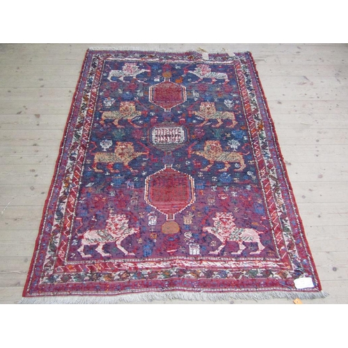 56 - An Iranian woollen rug of red, blue ground decorated with lions and flowers within three borders, 13... 