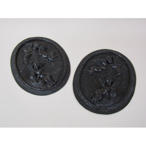 38 - A pair of patinated bronze oval plaques, after the original, two cherubs in the clouds & one cherub ... 