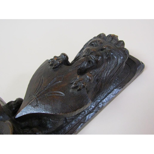 57 - A pair of 19c oak furniture mounts carved with lion and shield, over suspended bow and flowers, each... 
