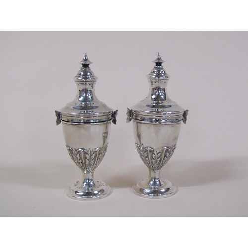 135 - A pair of Edwardian silver peppers of ovoid form, embossed and chased with leaf, having lift off cov... 