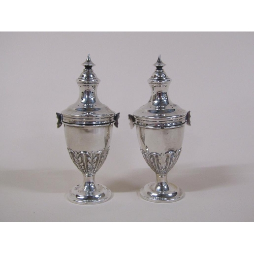 135 - A pair of Edwardian silver peppers of ovoid form, embossed and chased with leaf, having lift off cov... 