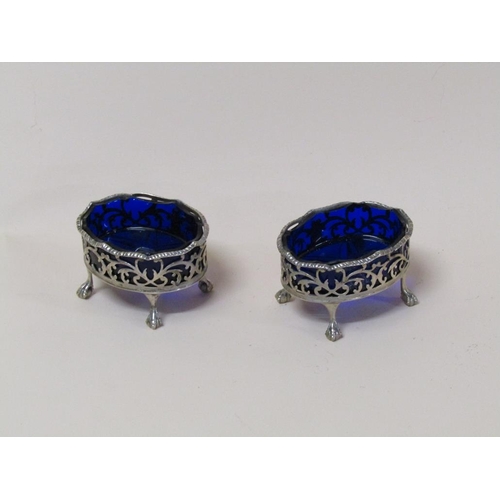 137 - A pair of mid Georgian silver table salts of pierced oval form with ball and claw feet, blue glass l... 