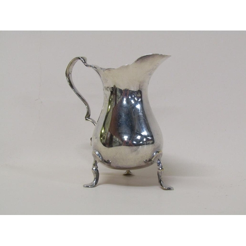 138 - A late Georgian silver cream jug of baluster form, having a double scroll handle on three legs with ... 