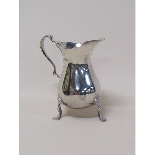 138 - A late Georgian silver cream jug of baluster form, having a double scroll handle on three legs with ... 