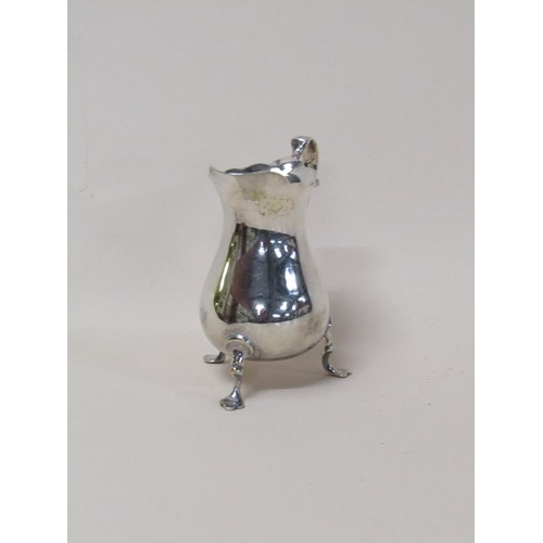 138 - A late Georgian silver cream jug of baluster form, having a double scroll handle on three legs with ... 