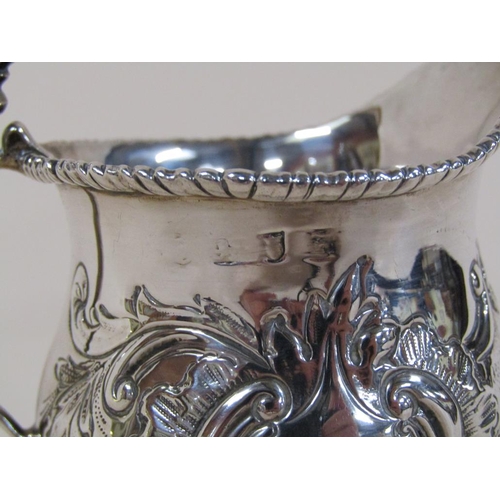 139 - A late 18c/early 19c silver cream jug, embossed and chased with beaded upper rim and base, having do... 