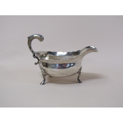 145 - A late Georgian silver sauce boat with open scroll handle, supported on three legs with hoof feet, m... 