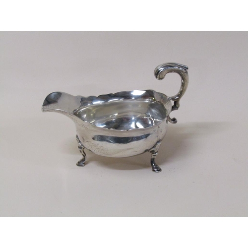 145 - A late Georgian silver sauce boat with open scroll handle, supported on three legs with hoof feet, m... 