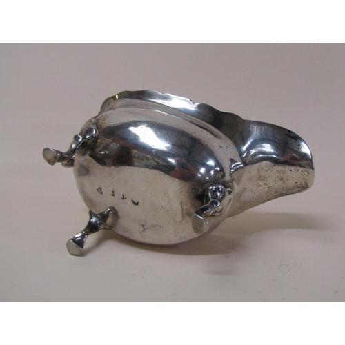 145 - A late Georgian silver sauce boat with open scroll handle, supported on three legs with hoof feet, m... 