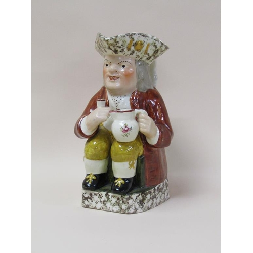 179 - A 19c Staffordshire toby jug, the base and rim dappled wearing a brown coat and yellow trousers, 27c... 