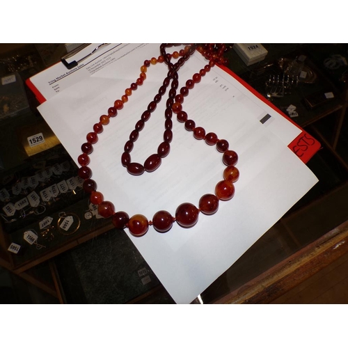 1525 - TWO STRINGS OF AMBER LIKE BEADS