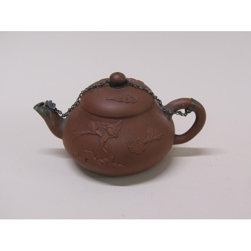 179 - A early Chinese terracotta teapot decorated in relief with flowers, with metal chain and spout, 10cm... 