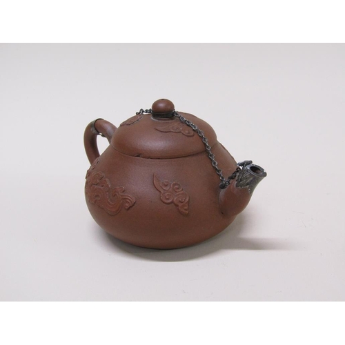 179 - A early Chinese terracotta teapot decorated in relief with flowers, with metal chain and spout, 10cm... 