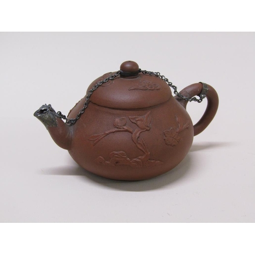 179 - A early Chinese terracotta teapot decorated in relief with flowers, with metal chain and spout, 10cm... 