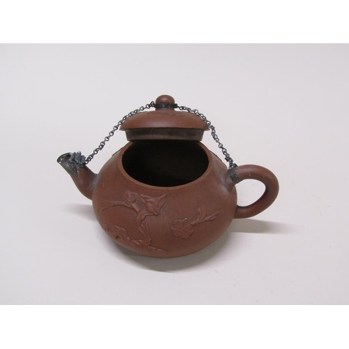 179 - A early Chinese terracotta teapot decorated in relief with flowers, with metal chain and spout, 10cm... 