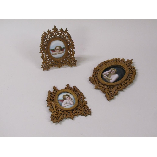 66 - Three 19c oval porcelain plaques, two of cherubs, 6cm x 5cm, and one of a lady reading a book, 8cm x... 