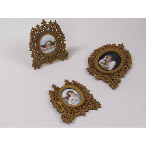 66 - Three 19c oval porcelain plaques, two of cherubs, 6cm x 5cm, and one of a lady reading a book, 8cm x... 