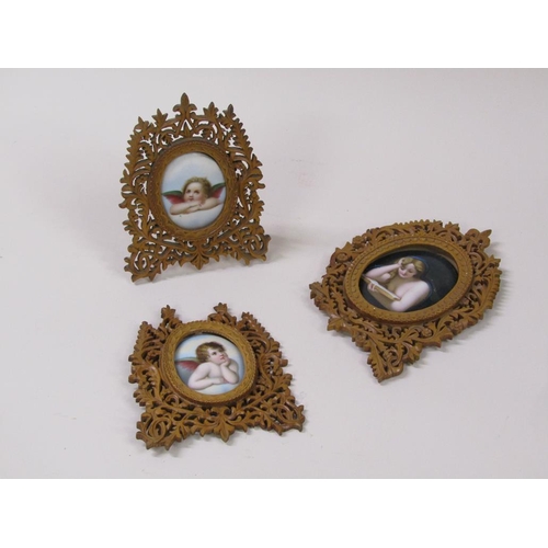 66 - Three 19c oval porcelain plaques, two of cherubs, 6cm x 5cm, and one of a lady reading a book, 8cm x... 