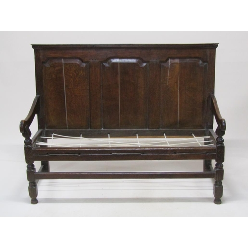 304 - An 18c oak three panel back settle with scrolling arms, on block carved legs with front stretcher ra... 