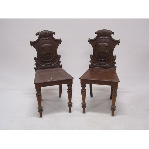 313 - A pair of Victorian mahogany hall chairs with shield carved backs, solid seats and baluster ring tur... 