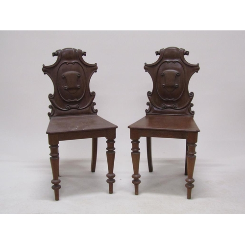 313 - A pair of Victorian mahogany hall chairs with shield carved backs, solid seats and baluster ring tur... 