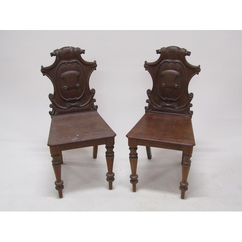 313 - A pair of Victorian mahogany hall chairs with shield carved backs, solid seats and baluster ring tur... 