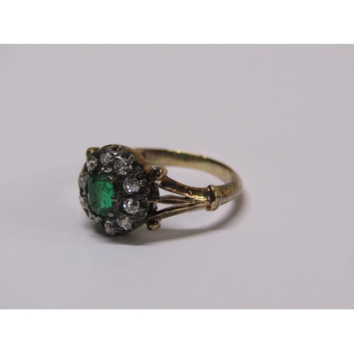 115 - An 18ct diamond and emerald ring with a central stone surrounded by ten diamonds, size L.