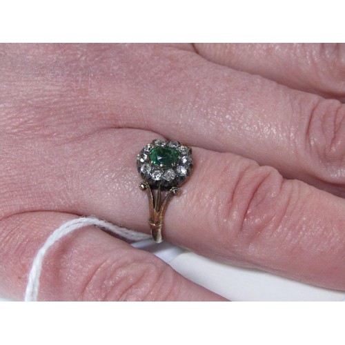 115 - An 18ct diamond and emerald ring with a central stone surrounded by ten diamonds, size L.