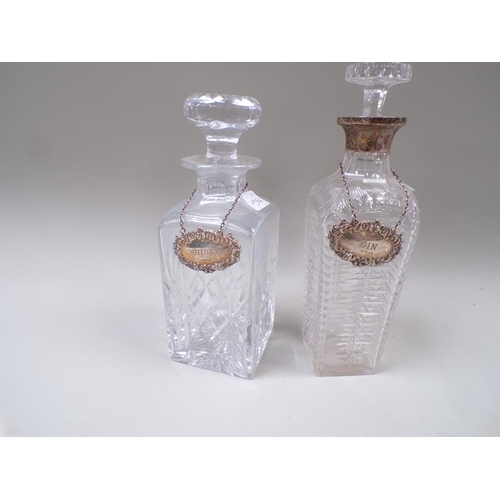 1662 - TWO CUT GLASS DECANTERS, ONE WITH A SILVER COLLAR AND TWO SILVER BOTTLE LABELS FOR WHISKY AND GIN