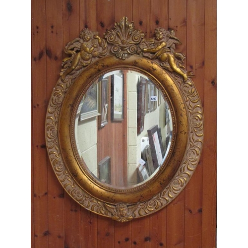 1217 - GILT WOOD AND STUCCO OVAL WALL MIRROR WITH CHERUB PEDIMENTS, 104CM X 98CM