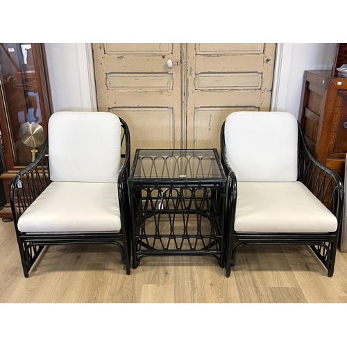 1200 - Modern three piece black lacquer cane suite, comprising a pair of arm chairs and glass topped square... 