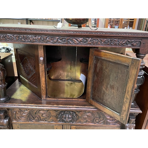 251 - An early 20th century Jacobean Revival oak court cupboard with carved decoration, fitted with three ... 