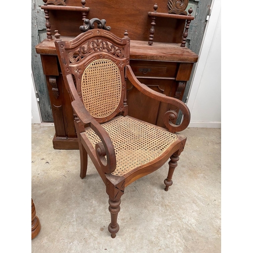 497 - South East Asian carved teak arm chair, caned seat and back