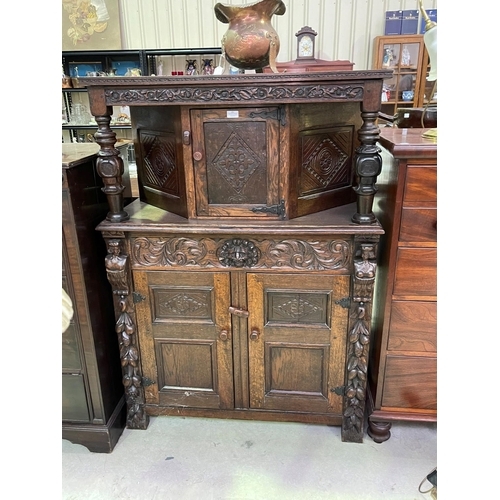 251 - An early 20th century Jacobean Revival oak court cupboard with carved decoration, fitted with three ... 