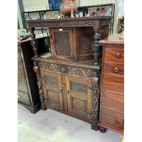 251 - An early 20th century Jacobean Revival oak court cupboard with carved decoration, fitted with three ... 