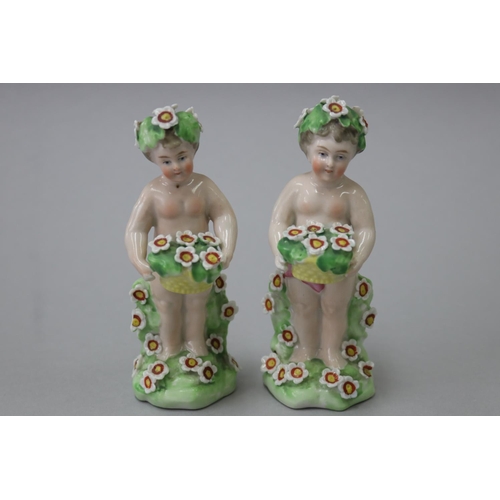 18 - Pair of Derby style porcelain putti with baskets of flowers, each approx 11.5cm H (2)