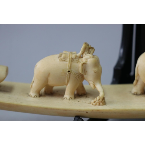 28 - Antique carved ivory tusk section, showing working elephants hauling logs, approx 30cm L