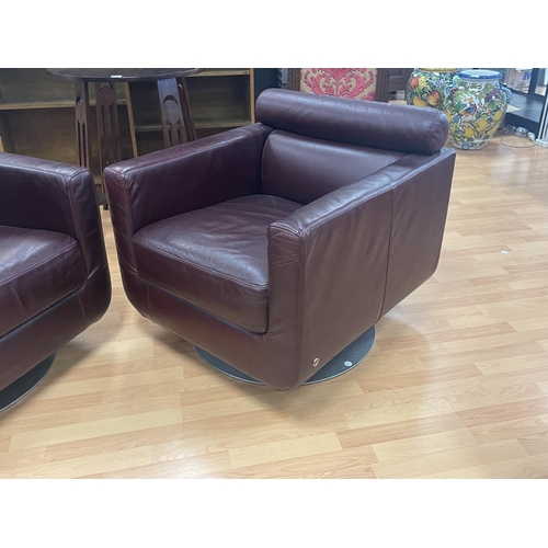 284 - Pair of Natuzi single chairs with a swivel bases, organic maroon leather, cylinder bolster head rest... 
