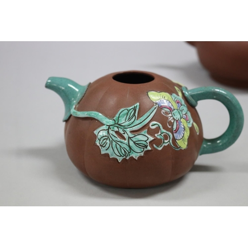 73 - Two Yixing Zhusha clay tea pots, one with raised painted decoration, the other of squat plain form, ... 