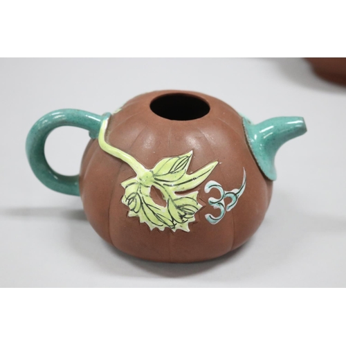 73 - Two Yixing Zhusha clay tea pots, one with raised painted decoration, the other of squat plain form, ... 