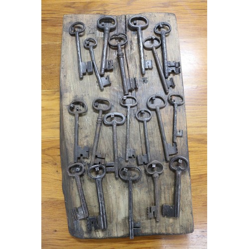 71 - Antique French iron keys on wooden backboard, approx 56cm x 31cm