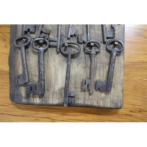71 - Antique French iron keys on wooden backboard, approx 56cm x 31cm