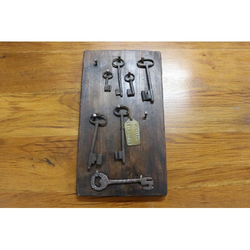70 - Antique French iron keys on wooden backboard, approx 40cm x 22cm