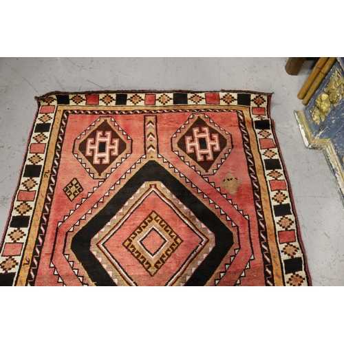 526 - Hand knotted wool carpet, of red ground with two diamond guls, approx 301cm x 152cm