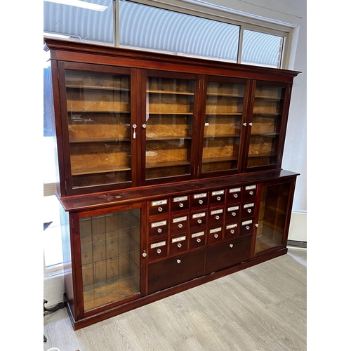 1048 - Rare Chemist two height shop cabinet, four sliding glazed doors over a two glazed door base with cen... 