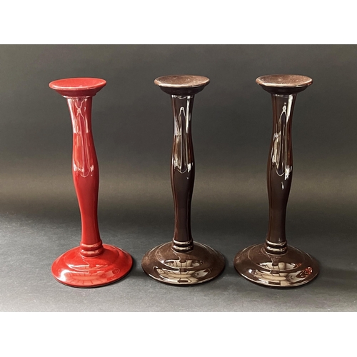 167 - Pair of brown candle sticks plus a red example, each approx 30cm H (3)