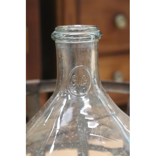 1110 - Antique French clear glass wine bottle in metal cradle, approx 50cm H x 50cm Dia