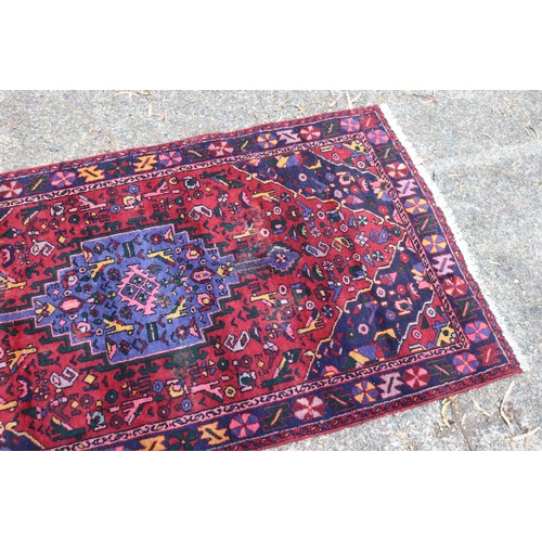 1040 - Handwoven red ground carpet, approx 240cm x 130cm