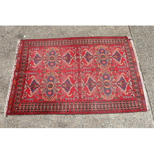 1044 - Handwoven wool carpet of red ground, approx 193cm x 130cm