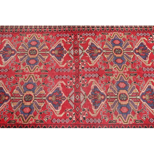 1044 - Handwoven wool carpet of red ground, approx 193cm x 130cm